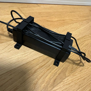 Parametrisk nätadapterhållare med kabelklämma